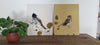 שני ציורי ציפורים מונחים על שידה